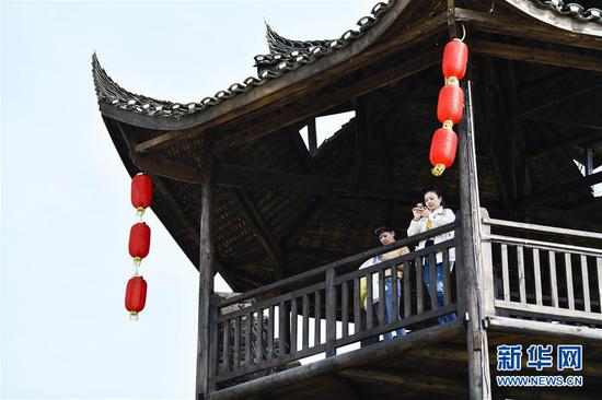  游客在重慶市武隆區(qū)黃鶯鄉(xiāng)復(fù)興村的觀景樓上欣賞田園景色（2019年3月28日攝）。 新華社記者 劉潺 攝